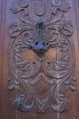 wooden door facade with openwork decor, and a forged large handle