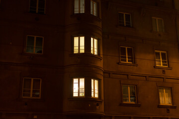 A tall building featuring numerous windows that are beautifully illuminated during the night hours, creating a stunning sight to behold