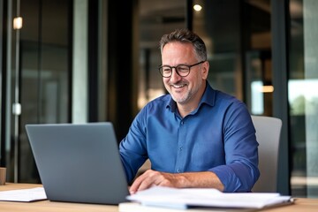 Middle-aged professional engaged in productive work with laptop in a bright office