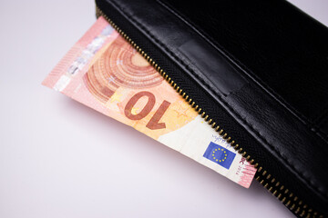 Black leather wallet with ten euro bills banknotes on white background 