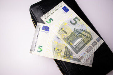 Black leather wallet with five euro bills banknotes on white background 