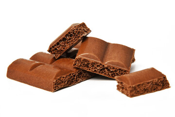 Chunks of porous milk chocolate in a pile on a white background