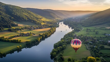 A colorful hot air balloon floating over a picturesque valley at sunrise.