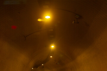 A blurry image depicting a street light surrounded by fog on a dark night, creating an atmospheric...