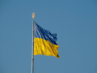 A clear-sky photograph of a simple, two-colored flag yellow upper band, blue lower band mounted on a structure No text or visible emblems Taken during the day under bright conditions