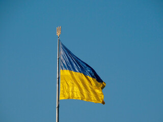 A clear image of Ukraines flag flying against a blue sky, mounted on a building or structure with a sharp focus