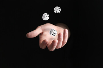 Man throwing white dice in darkness, closeup
