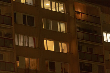 A large and modern building with numerous windows is beautifully illuminated during the night, creating a stunning urban atmosphere