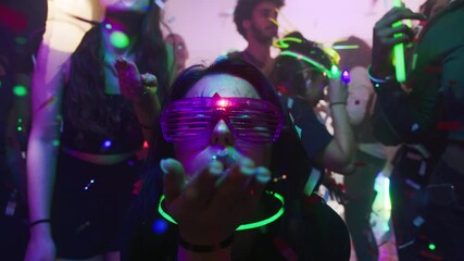 Electric Vibes: Woman with Futuristic Glasses Enjoying Confetti Blast at Vibrant Party Scene
