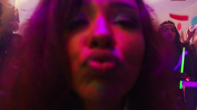 Shot where an attractive woman in a house party looks at the camera and kisses the lens.