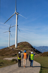 multiethnic Engineers walking and inspecting wind turbines on mountain top
