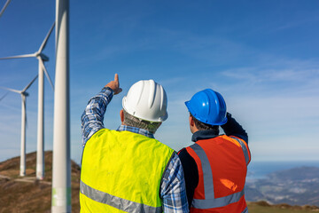 Engineers pointing at wind turbines, discussing green energy