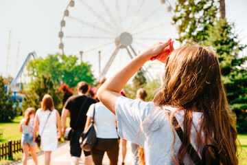 Obraz premium A young girl in an amusement park with a Ferris wheel in the background.
