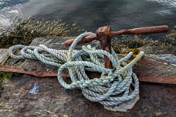 Old rusty mooring bollard in fjord harbor in Norway.