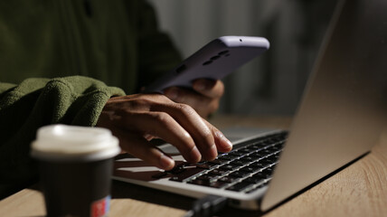 Programmer is working on laptop and using smartphone at night