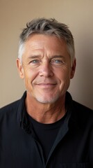 Obraz premium Man with gray hair and blue eyes smiles warmly while wearing a black shirt