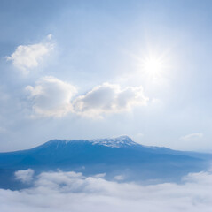 mountain chain silhouette in blue mist under a sparkle sun