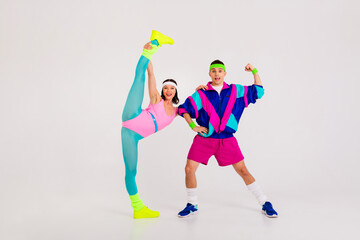 Energetic couple embracing retro fashion style as they pose in vibrant sportswear on white background showcasing aerobics