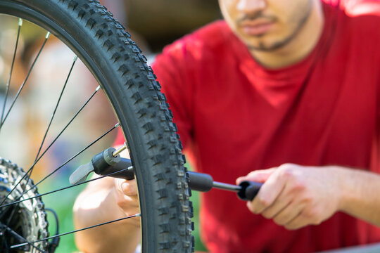 Close up of a man pumping up a bike tire using small hand pump