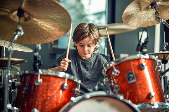 Young caucasian male child playing drums in a music studio setting