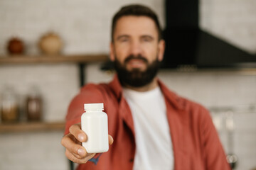 Happy young man holding a medicine bottle close up.  Painkiller, headache medication or vitamins...