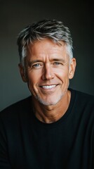 Obraz premium Man with gray hair and blue eyes smiles warmly while wearing a black shirt