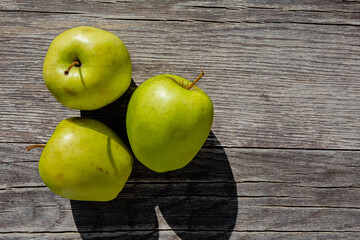 Fresh green apples on an old wooden countertop, creating a rustic and natural atmosphere. Perfect for healthy living themes, farm-to-table or vintage kitchen decor, adding a fresh and organic touch.
