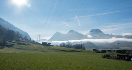 Switzerland landscape with swiss fields and alpine mountains under electric power lines in...