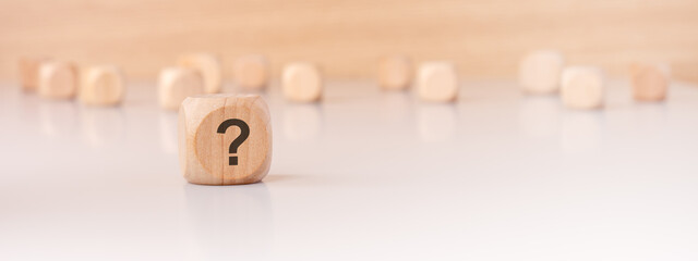 A wooden block with a question mark on a minimal background creates intrigue and prompts thought