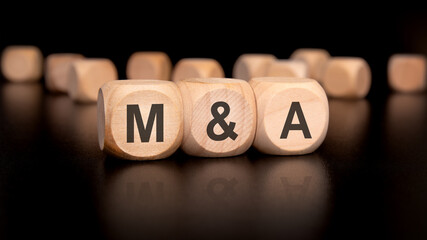 MA Concept Mergers and Acquisitions Wooden Blocks, examining business growth dynamics