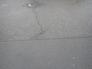 asphalt road with broken cracks after rain