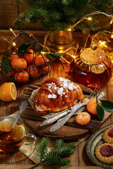 Croissant with tea and tangerines on a wooden background