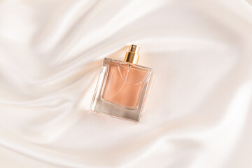 Elegant square perfume bottle on silky fabric background