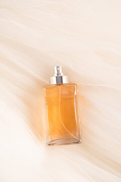 Elegant square perfume bottle with amber liquid on fabric background