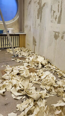 A ladder is leaning against a wall with a pile of paper on the floor