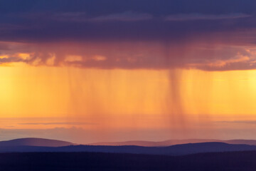 Heavy rainfall over some fells during a colorful sunset in Riisitunturi National Park, Northern...