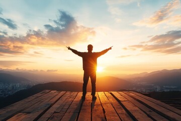 Fototapeta premium Individual enjoying a sunset atop a mountain with arms outstretched, embracing nature's beauty