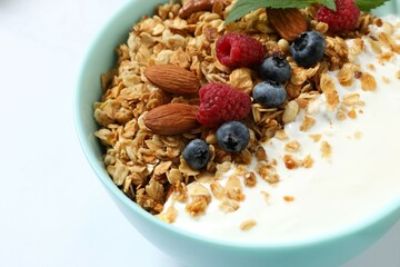 Delicious granola with berries and yogurt on a light background