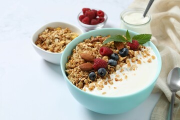 Delicious granola with berries and yogurt on a light background