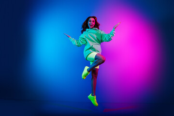 Obraz premium Full length photo of shiny excited lady dressed green sweatshirt jumping high empty space isolated blue light color background