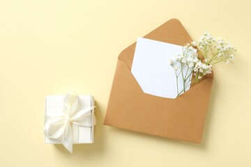 Top view photo with paper envelope, gift box and gypsophila flowers on color background 