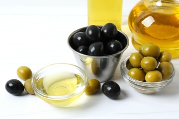 Bowl of fresh olive oil and olives with leaves on the table