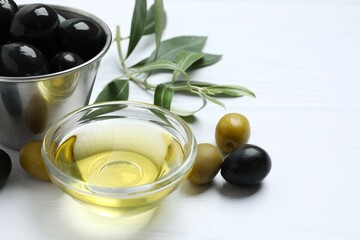 Bottles of fresh olive oil and olives with leaves on the table