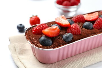 Delicious tiramisu cake with berries on table