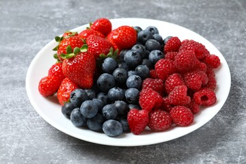 Different fresh ripe berries in bowl on wooden table
