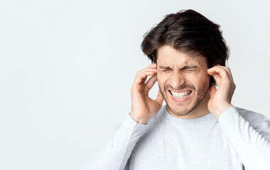 Ear pain concept. Man grimaces and touches ears, free space