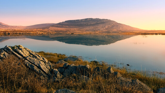 Beautiful sunrise landscape scenery of Mullaghmore mountain reflected in Lake at Burren National Park in county Clare, Ireland, nature background	