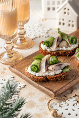 Little sandwiches bruschettas with pieces of salted herring cream cheese and cucumber. Traditional new year appetizer. Festive table