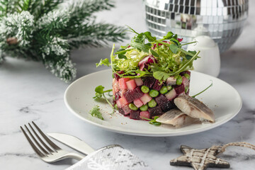 Traditional Russian and Ukrainian vegetable salad Vinaigrette for celebrating new year. Salad with beets, potatoes, cucumbers and peas served with slices of herring