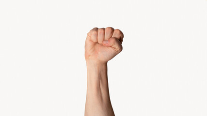 Millennial man raising his clenched fist up over light background, close up view. Panorama